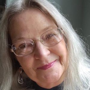 Virginia is a woman in her 60s with shoulder length grey/blond hair and glasses.